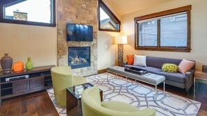 A modern living room with a stone fireplace, comfortable seating, and large windows. - Frisco Condo w/ Rooftop Deck: Walk to Main St! (Frisco)