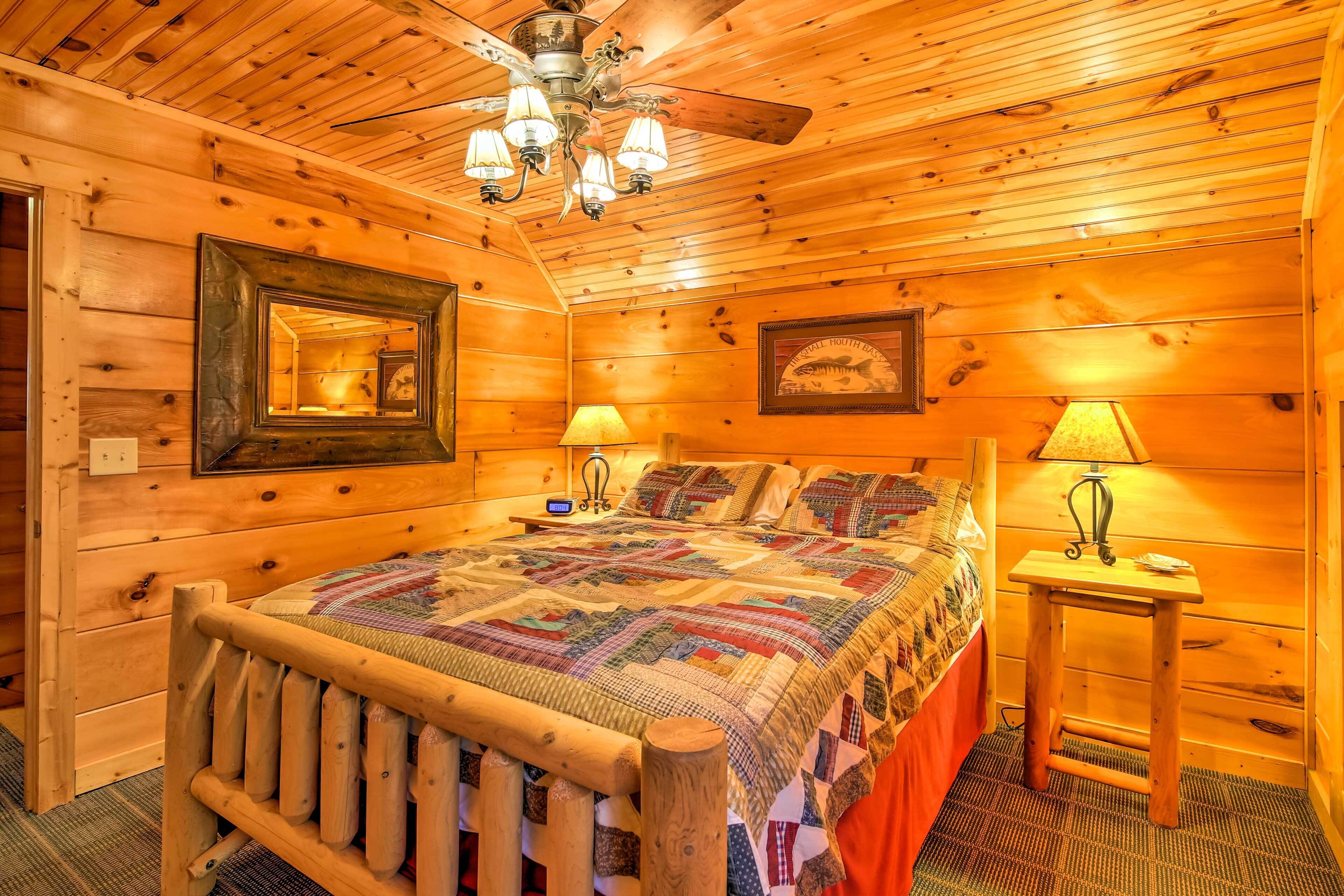 Een slaapkamer in een houten chalet met een groot bed, een plafondventilator en twee bedlampjes.