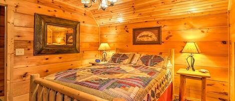 Een slaapkamer in een houten chalet met een groot bed, een plafondventilator en twee bedlampjes.