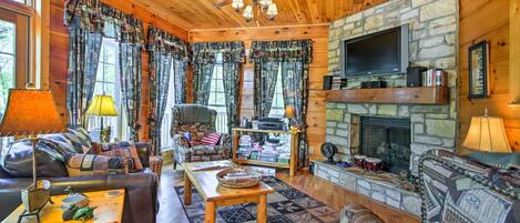 Interior acogedor de una cabaña con chimenea de piedra, techo de madera y una zona de estar confortable.