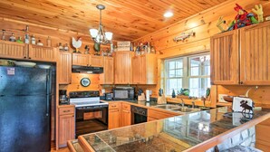 Cocina con armarios de madera, refrigerador, microondas, estufa y una isla con encimera de vidrio.