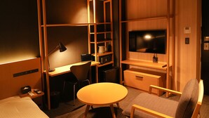 A compact hotel room with a bed, a desk, a chair, a round table, a TV, and built-in shelving. - Nplus hotel akihabara (Tokyo)