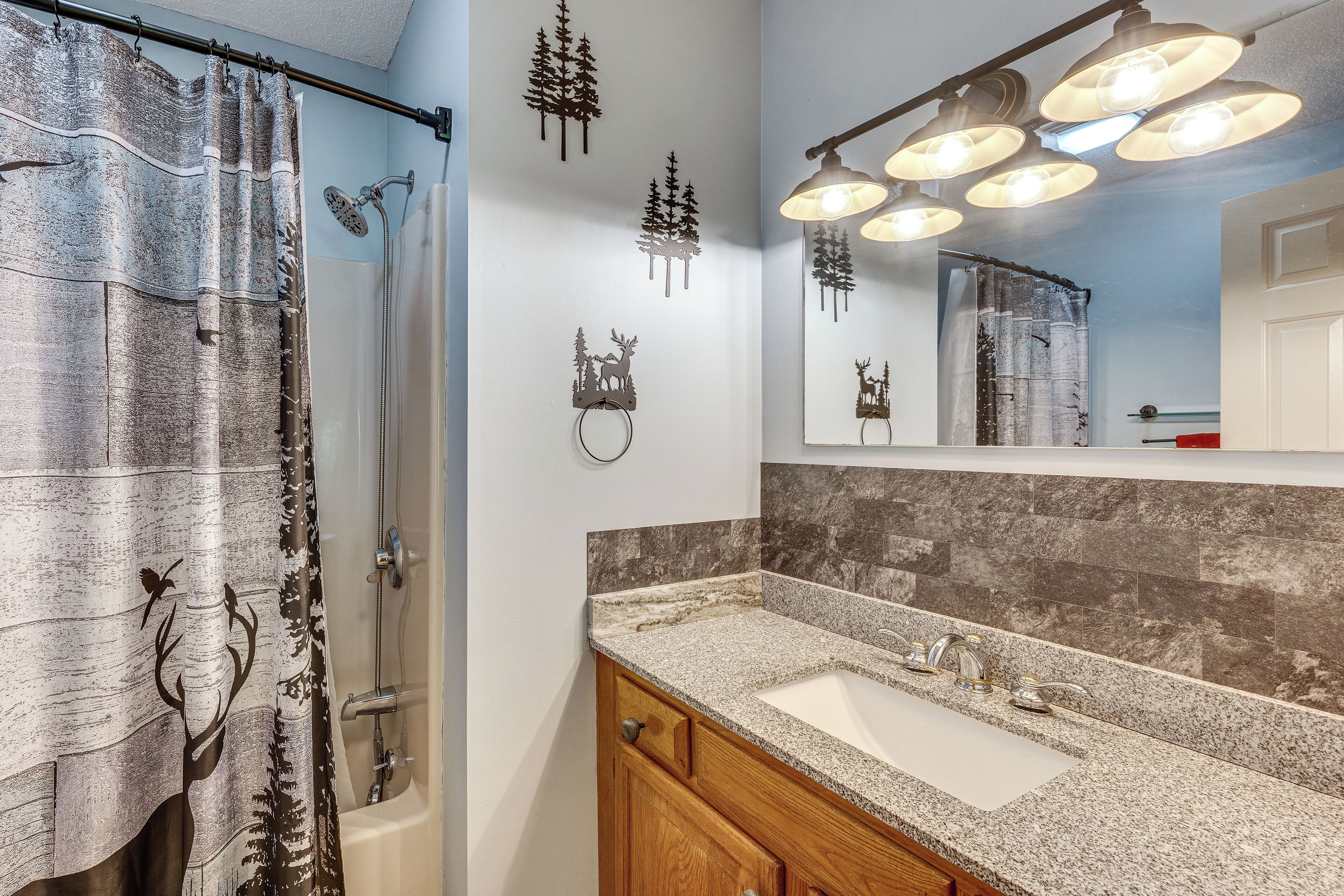 A bathroom with a shower, a sink, a mirror, and wall-mounted lights.