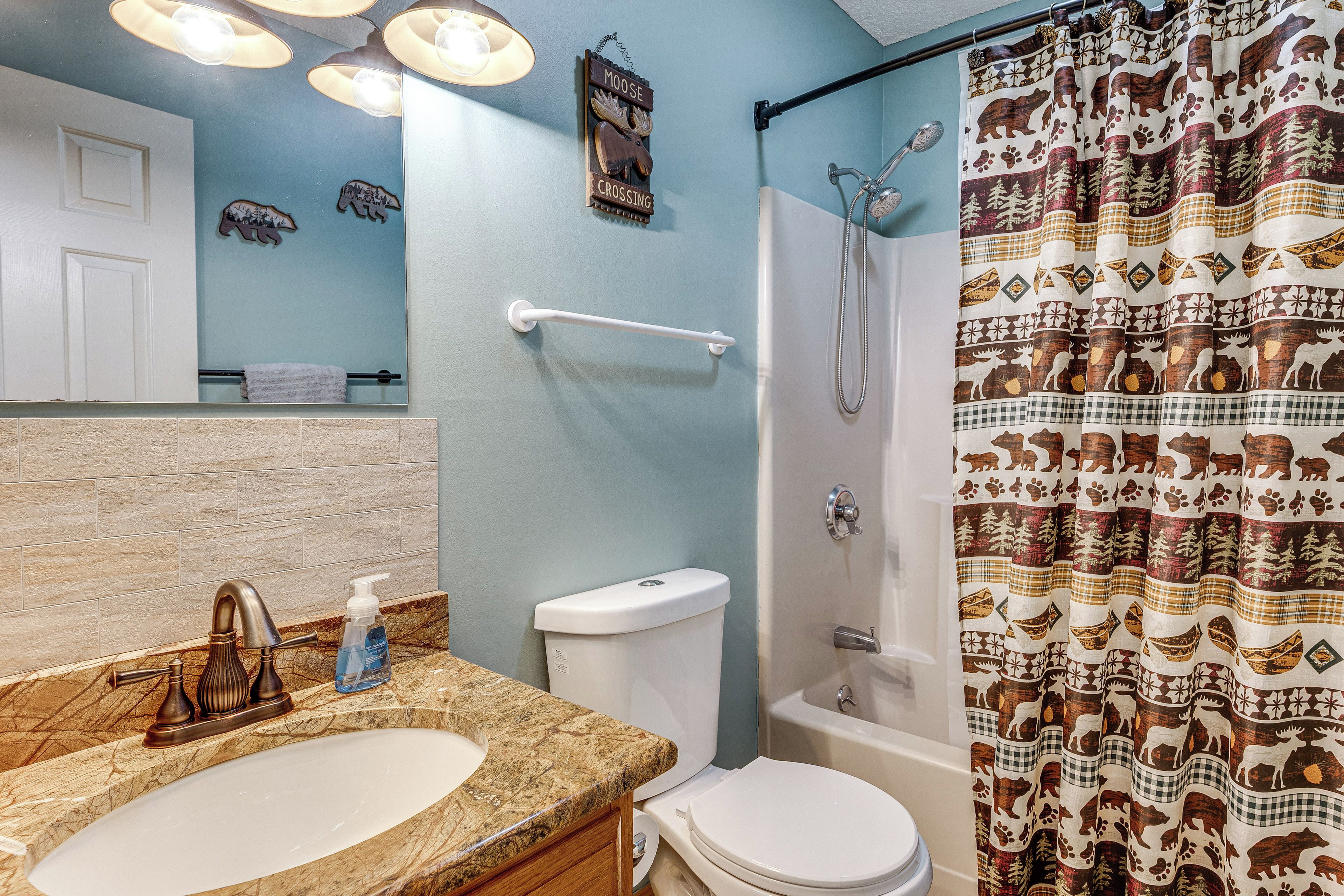 Une salle de bain équipée d’un lavabo, de toilettes, d’une douche et d’un rideau de douche à motifs d’élans.