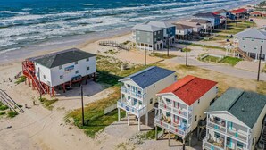 A beachfront hotel with multiple buildings, including a prominent white building with a red roof and a balcony. - Walk to Shore & Eats: Surfside Beach House (Freeport)