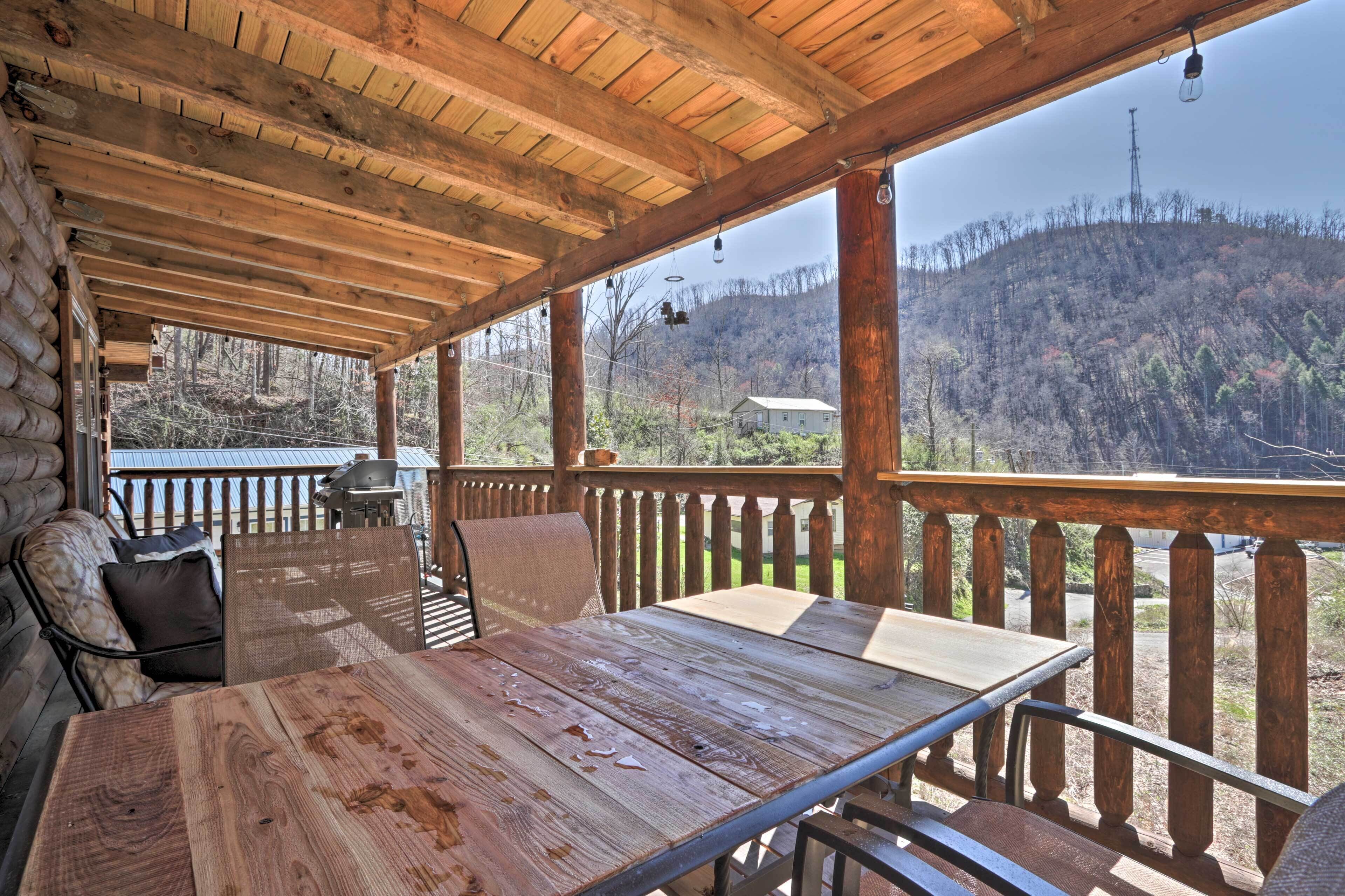 Une terrasse en bois avec une table et des chaises, donnant sur une colline boisée.