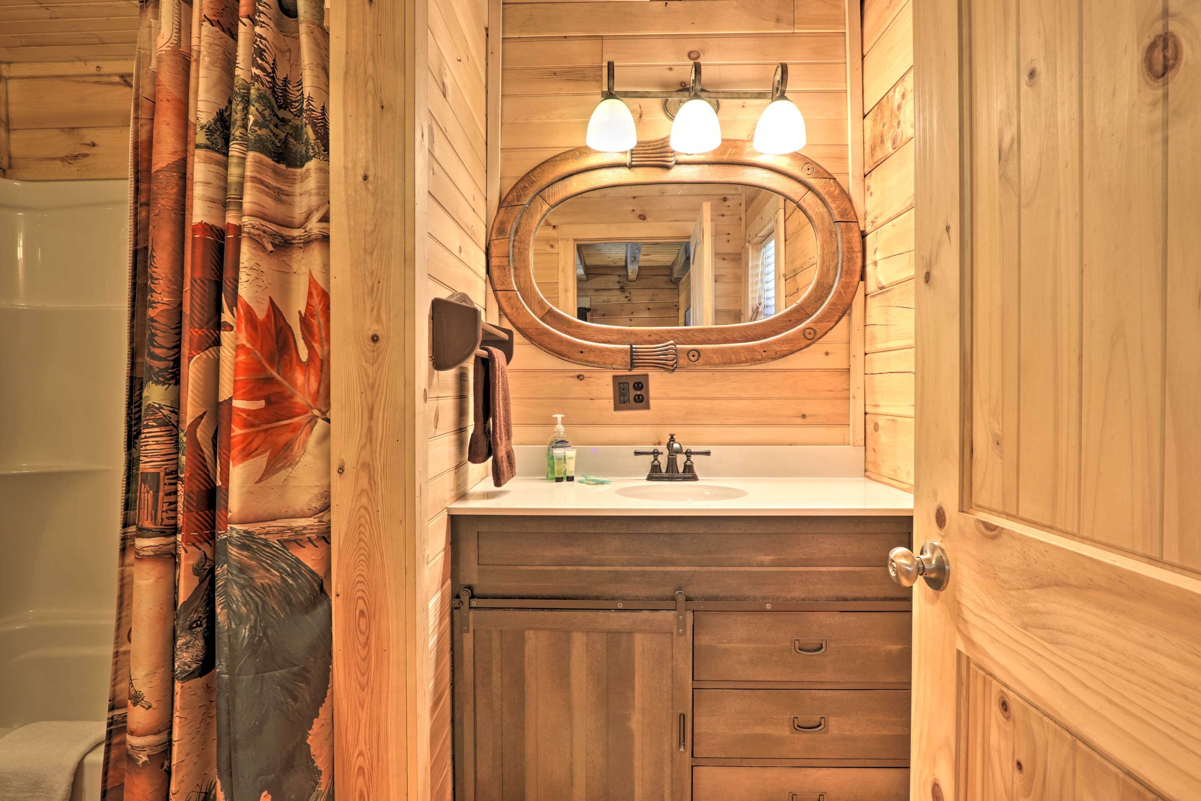 A wooden bathroom with a wooden vanity, a mirror, and a shower curtain with a leaf pattern.