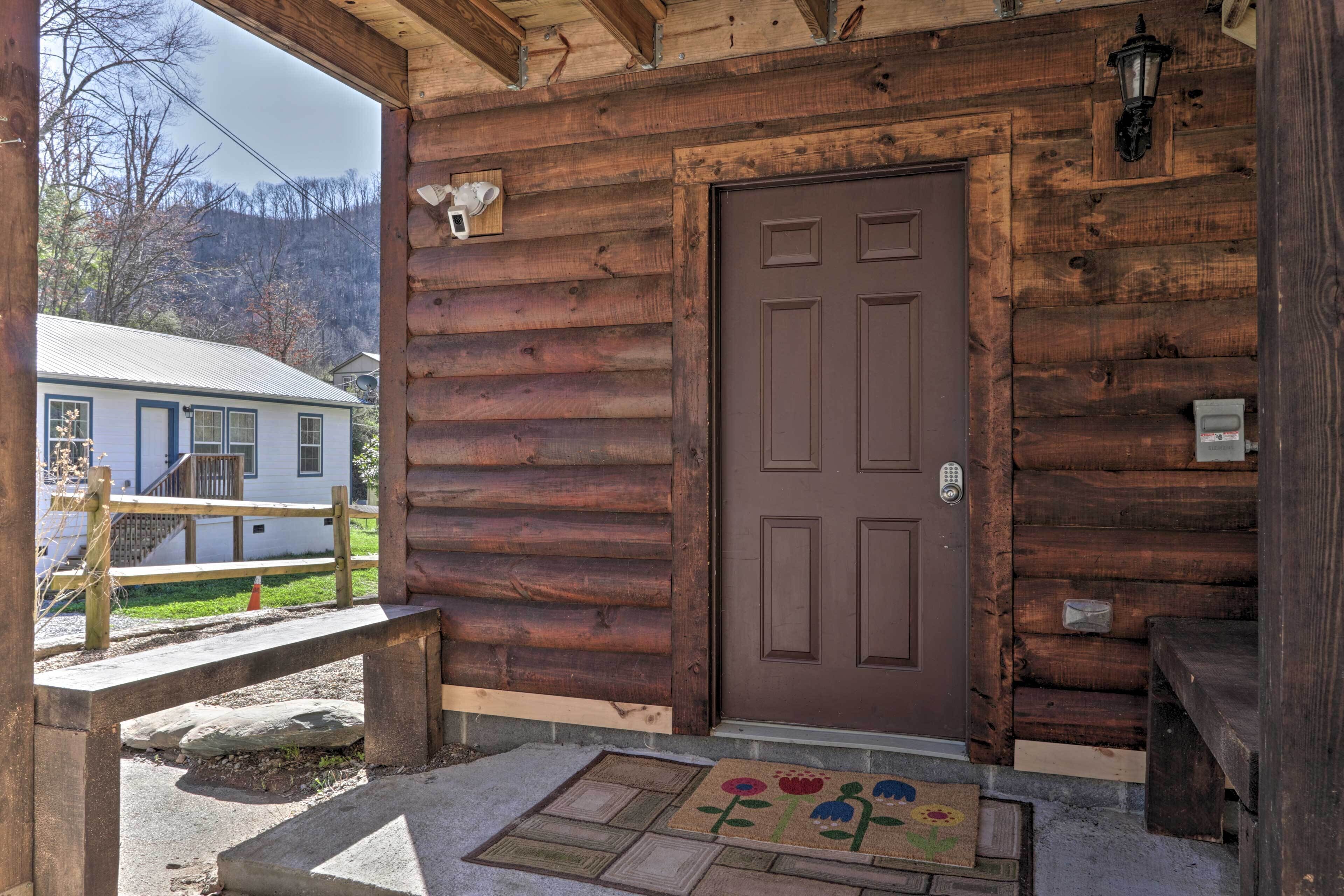 A wooden cabin with a brown door, a wooden bench, and a doormat with a floral design.