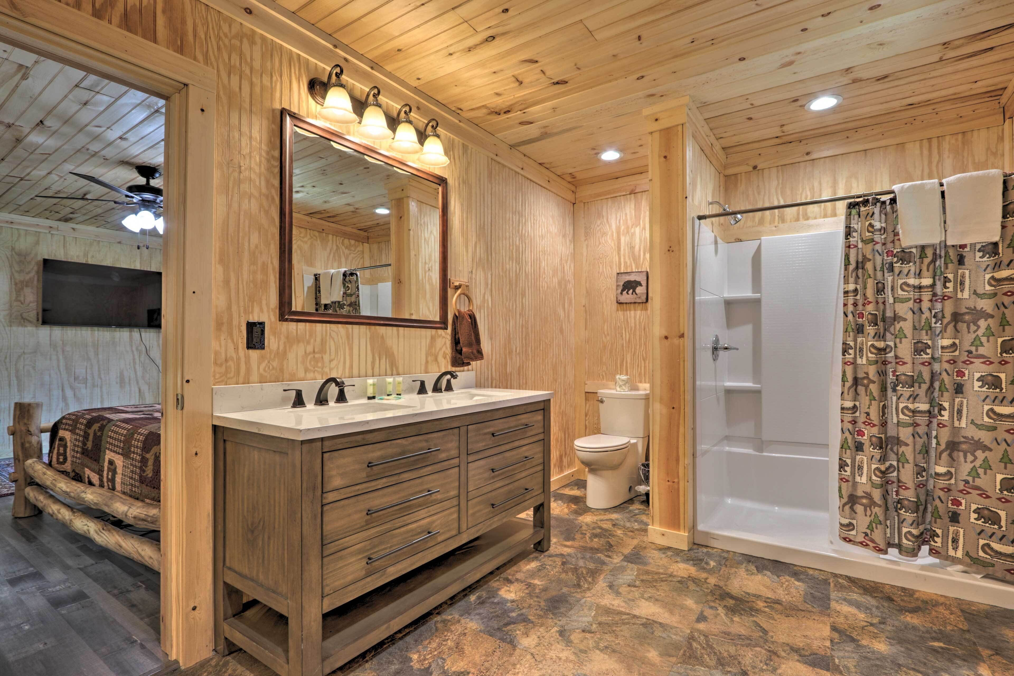 A wooden cabin bathroom with a wooden vanity, a large mirror, a toilet, and a shower with patterned curtains.
