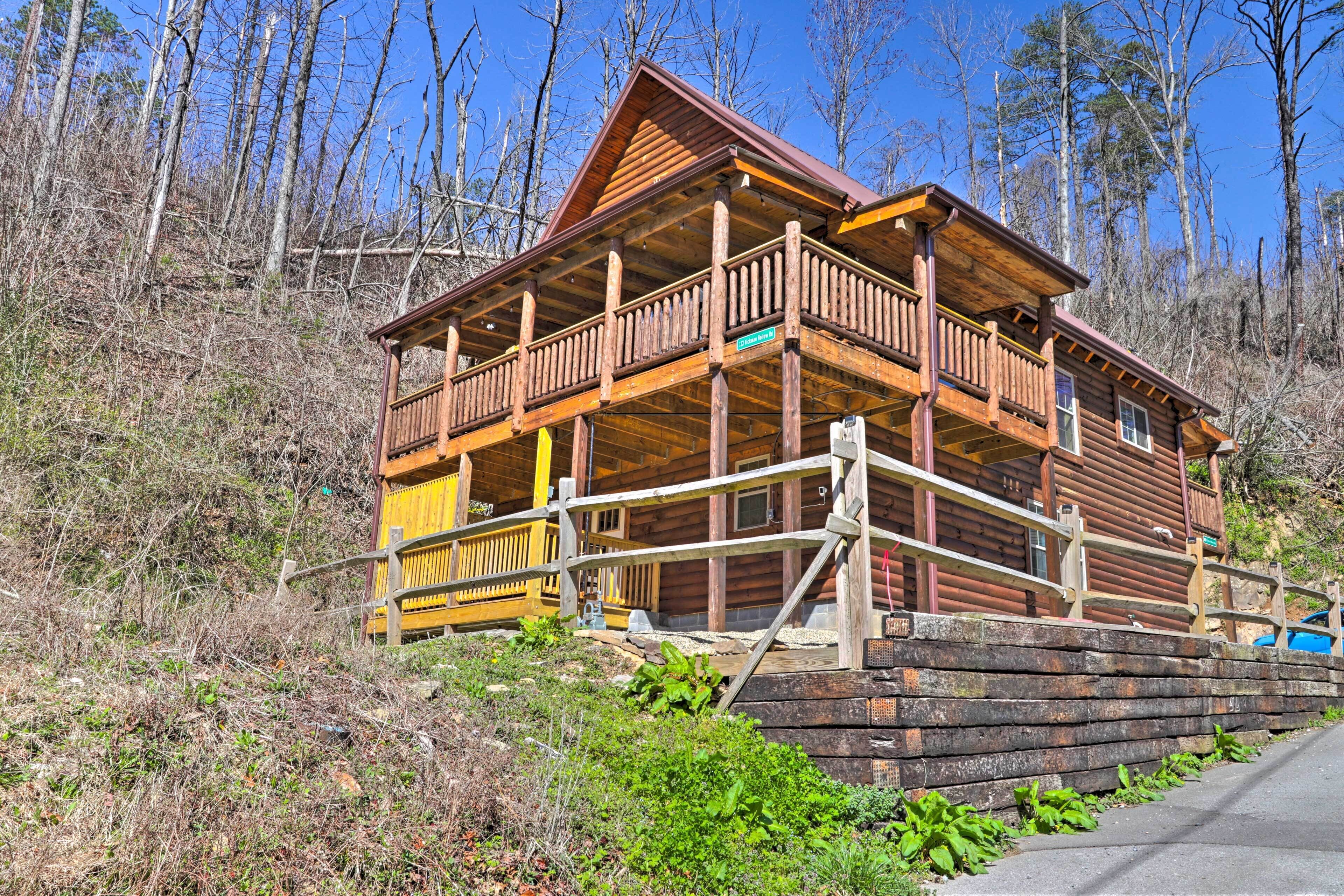 A wooden cabin with a balcony, surrounded by trees.