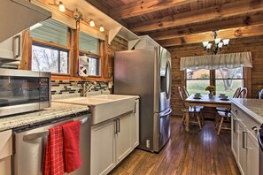 A modern kitchen with stainless steel appliances, wooden cabinets, and a dining area with a table and chairs.