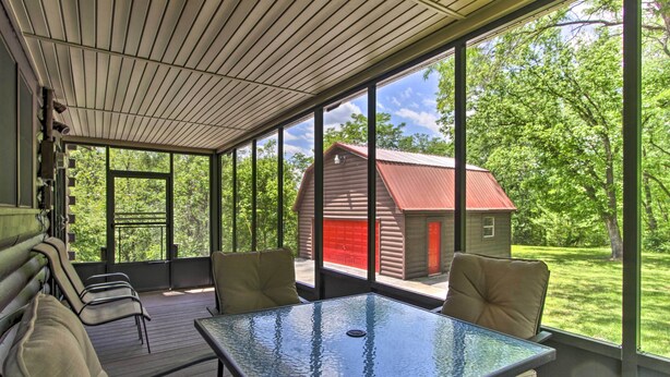 A covered outdoor seating area with a glass table and chairs, overlooking a red barn and lush greenery. - Rustic Cabin w/ Screened Deck: 8 Mi to Dollywood (Sevierville)