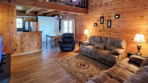 A cozy log cabin interior with a wooden dining area, a plush sofa, and a rug. - Rustic Cabin w/ Screened Deck: 8 Mi to Dollywood (Sevierville)