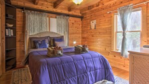 A wooden cabin bedroom with a bed, a nightstand, a shelf with books, and a window with curtains. - Rustic Cabin w/ Screened Deck: 8 Mi to Dollywood (Sevierville)