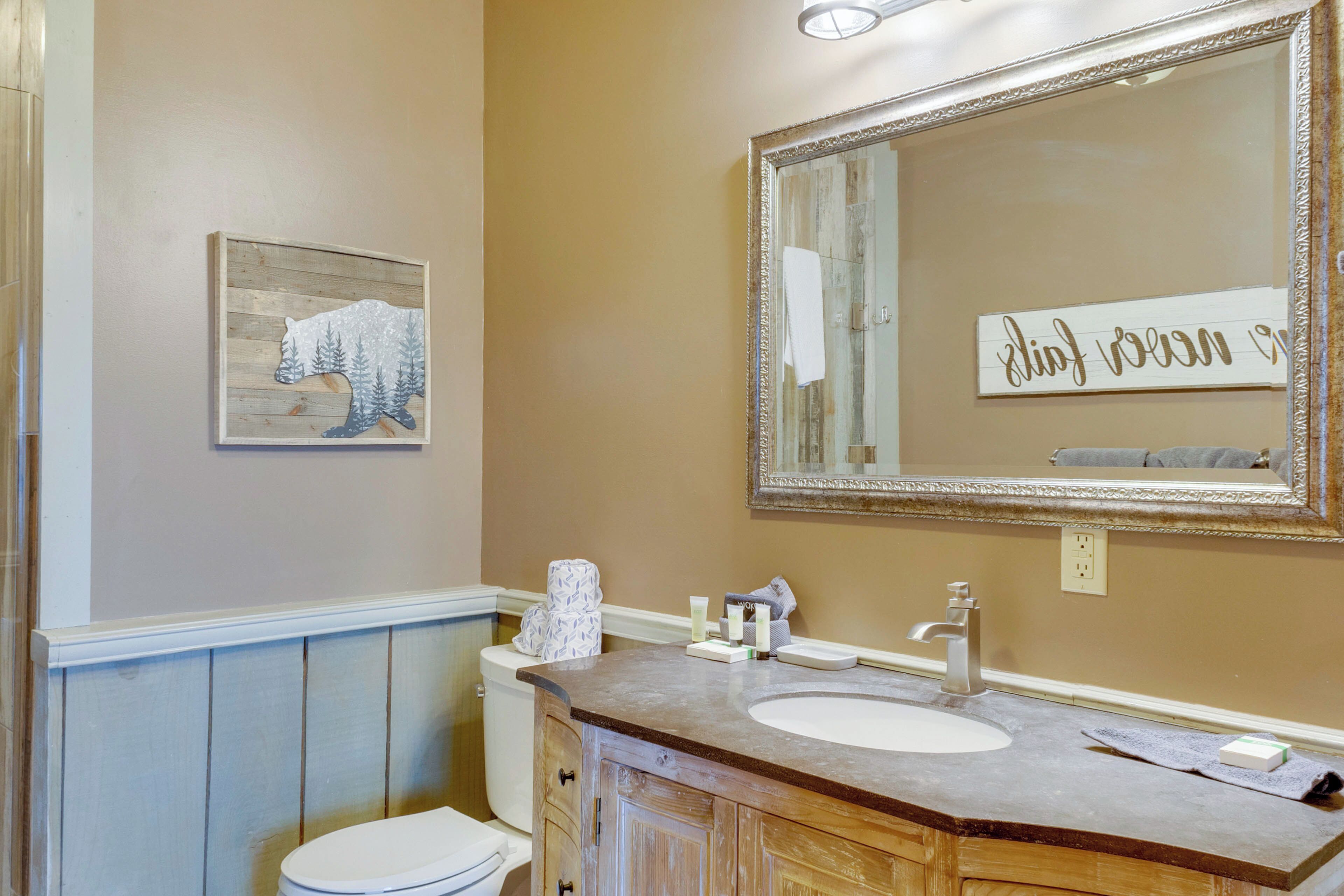 A bathroom with a wooden vanity, a large mirror, and a painting of a bear on the wall.