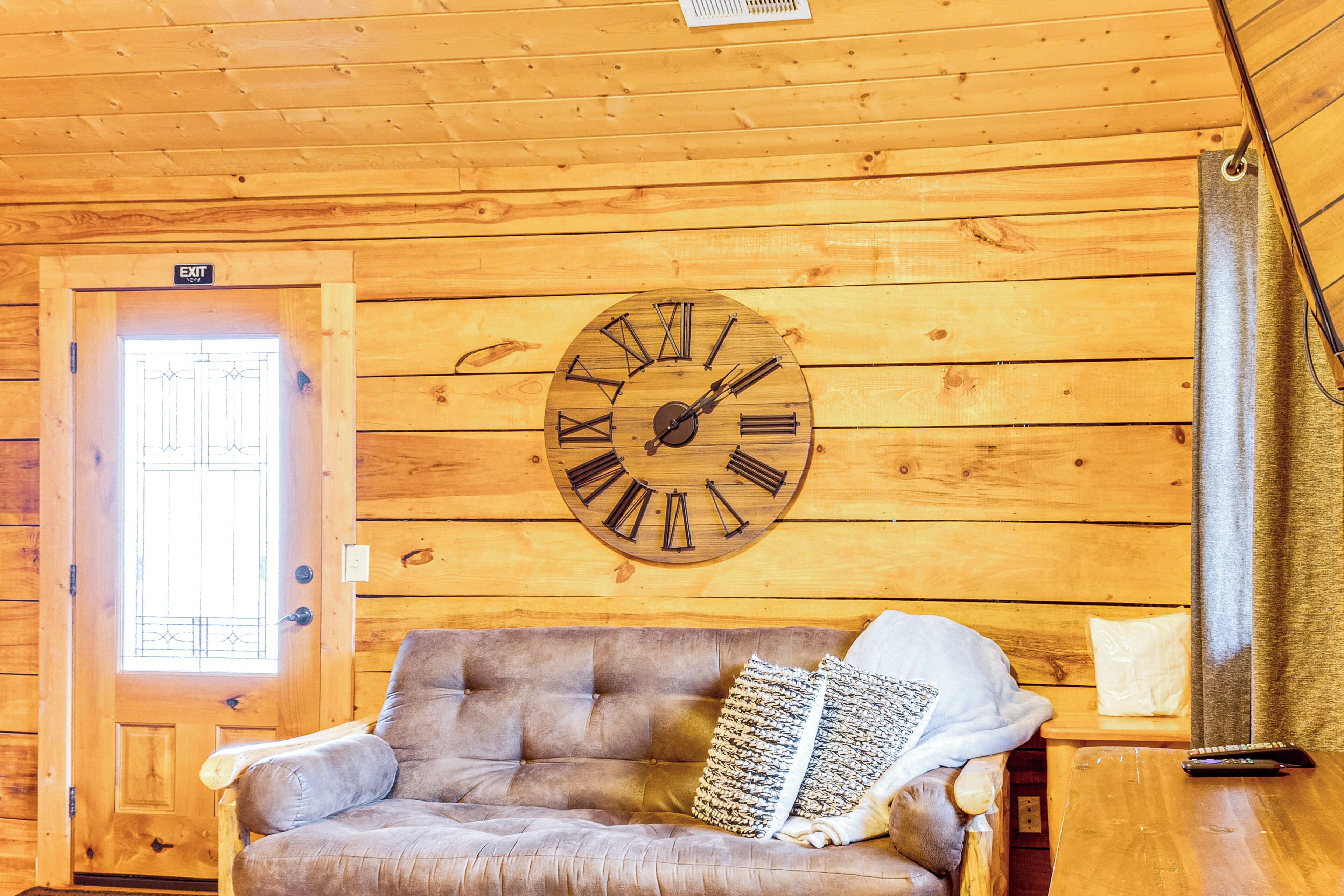 Un intérieur en bois avec une horloge, un canapé et une porte.
