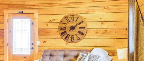 Un intérieur en bois avec une horloge, un canapé et une porte.