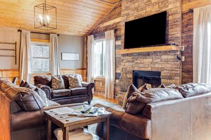 Ein gemütliches Wohnzimmer mit Ledersofas, einem Kamin und einem flachbildfernseher an einer Ziegelwand.