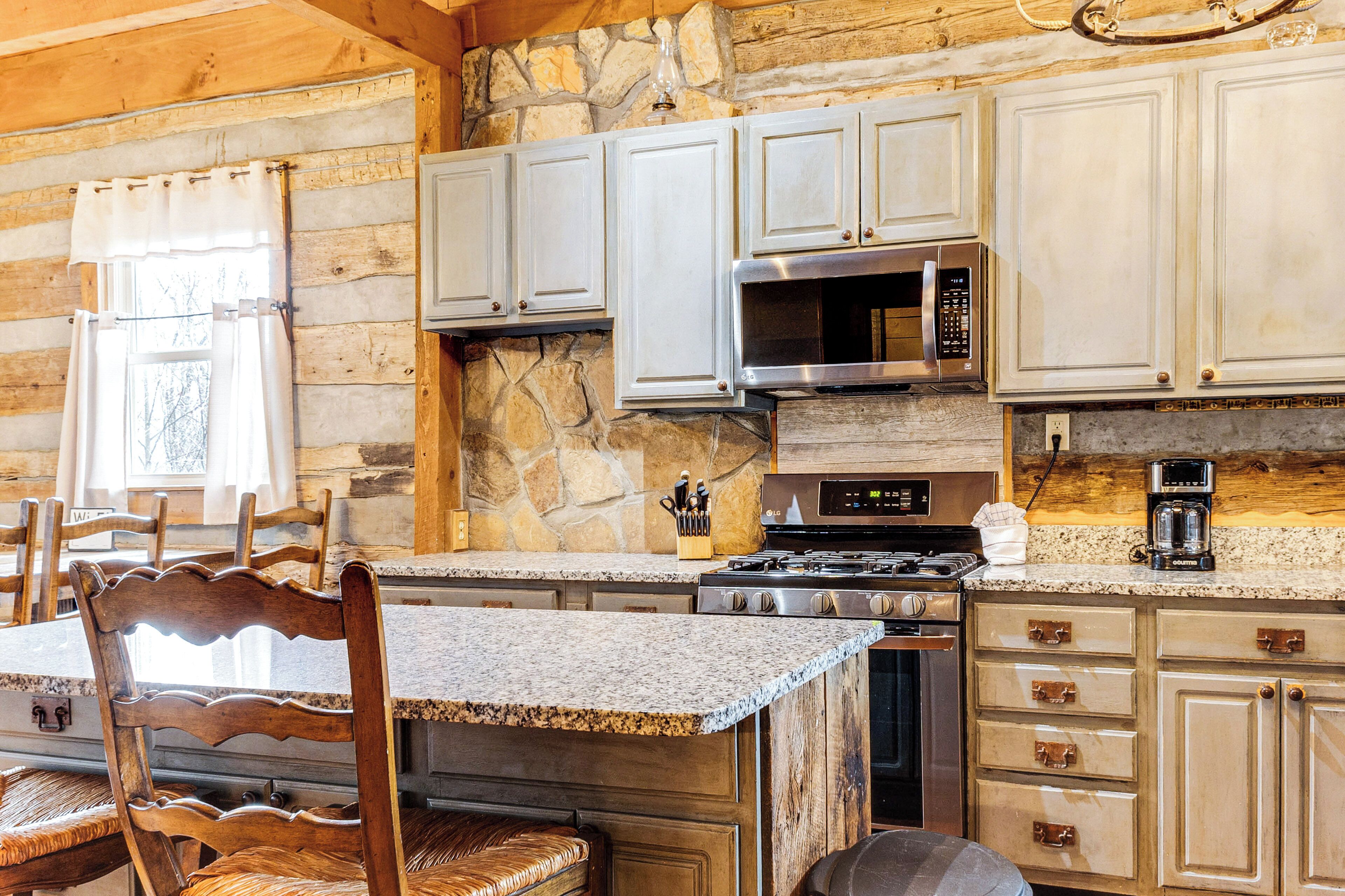 Una cocina rústica con paredes de piedra, armarios de madera y encimera de granito.