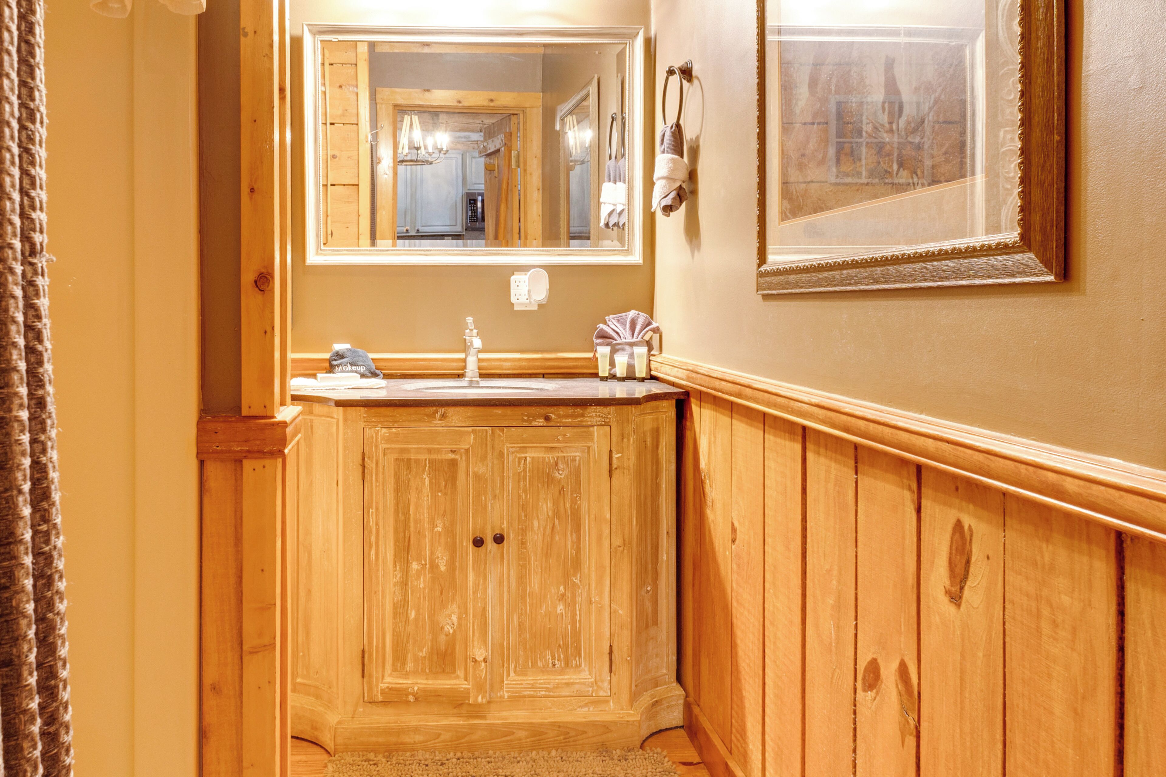 A wooden bathroom with a large mirror, wooden cabinets, and a sink.