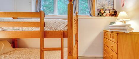 Habitación con literas, un aparador de madera y una ventana con cortinas.