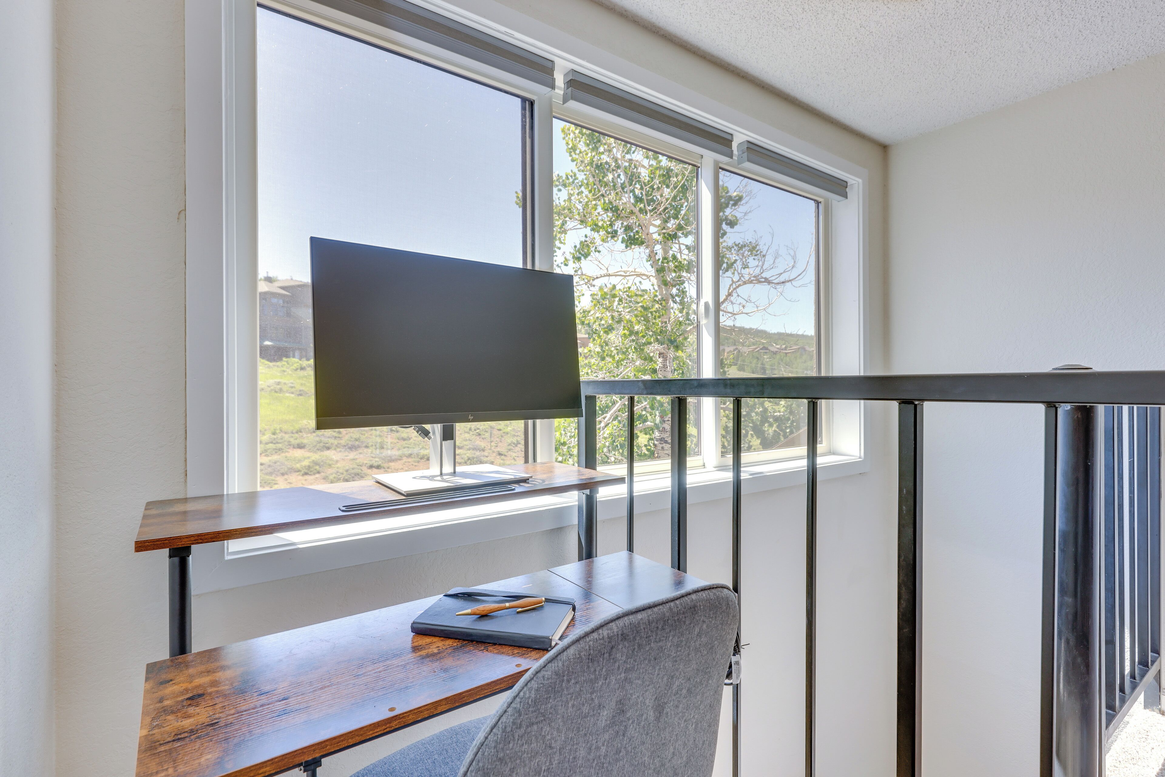 A modern room with a desk, chair, and a TV mounted on the wall.