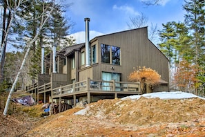 A modern multi-story building with a wooden deck, large windows, and a chimney. - Conway Condo w/ Hot Tub: Near Cranmore Skiing! (North Conway)