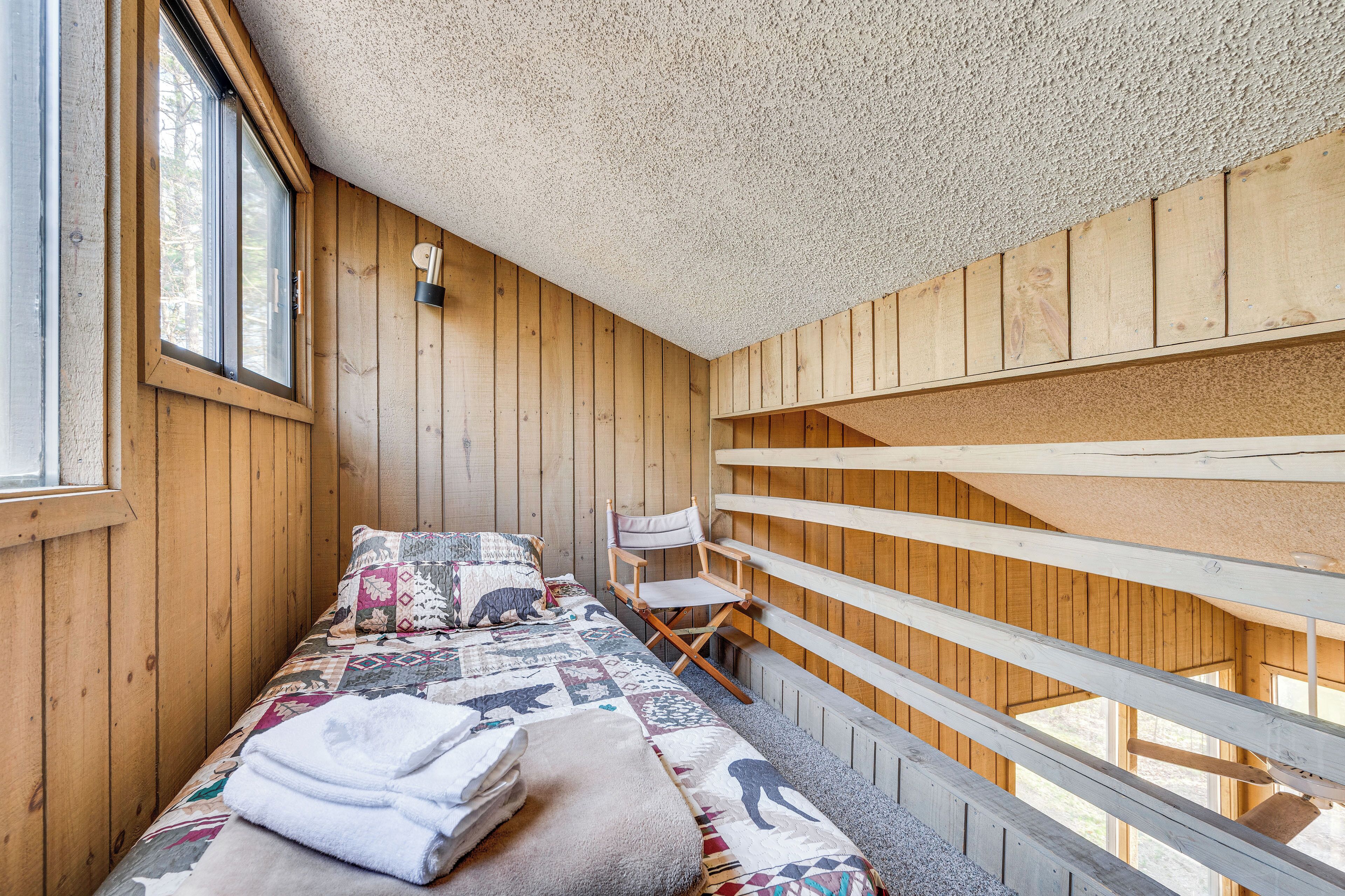 Une pièce dans un chalet en bois, avec un lit, une chaise et une fenêtre.