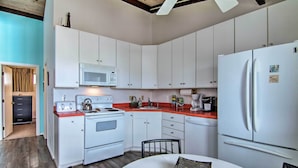 A kitchen with white cabinets, a white refrigerator, a microwave, a stove, and a sink. - Walk to Dewey Beach: Bright Condo w/ Balcony! (Dewey Beach)