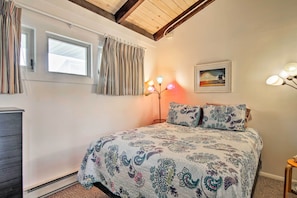 Une chambre à coucher avec un lit, des rideaux, une lampe sur pied, un tableau au mur et une fenêtre.