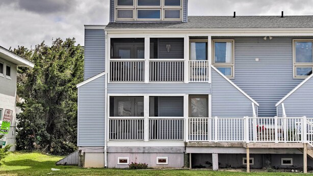 A two-story residential building with a balcony, a garage, and a small front yard. - Walk to Dewey Beach: Bright Condo w/ Balcony! (Dewey Beach)