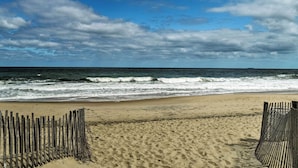 A beach with a wooden fence and waves crashing onto the shore. - Walk to Dewey Beach: Bright Condo w/ Balcony! (Dewey Beach)