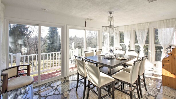 A dining area with a table and chairs, large windows, and a chandelier.