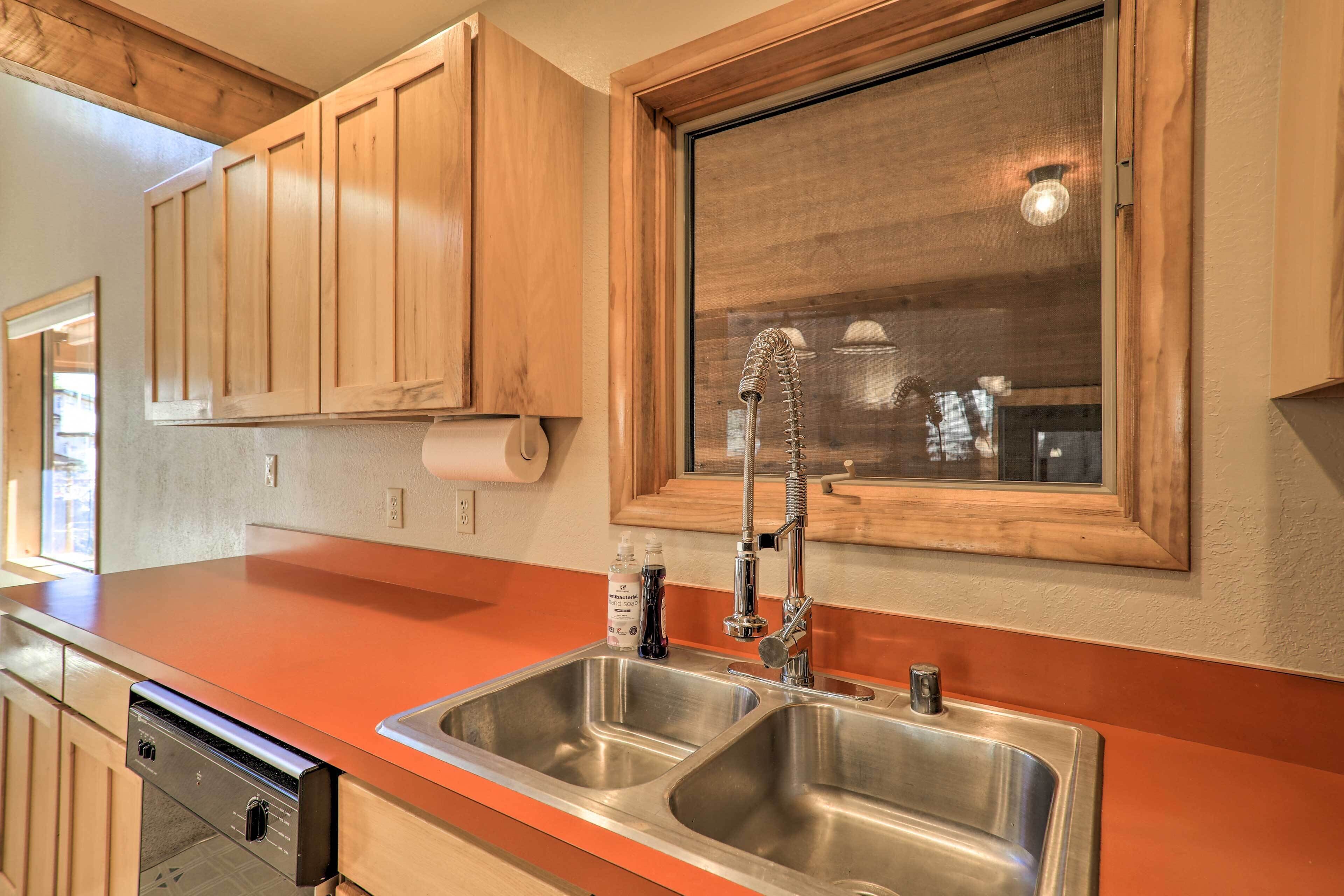 A kitchen with wooden cabinets, a stainless steel sink, and a window above the sink.