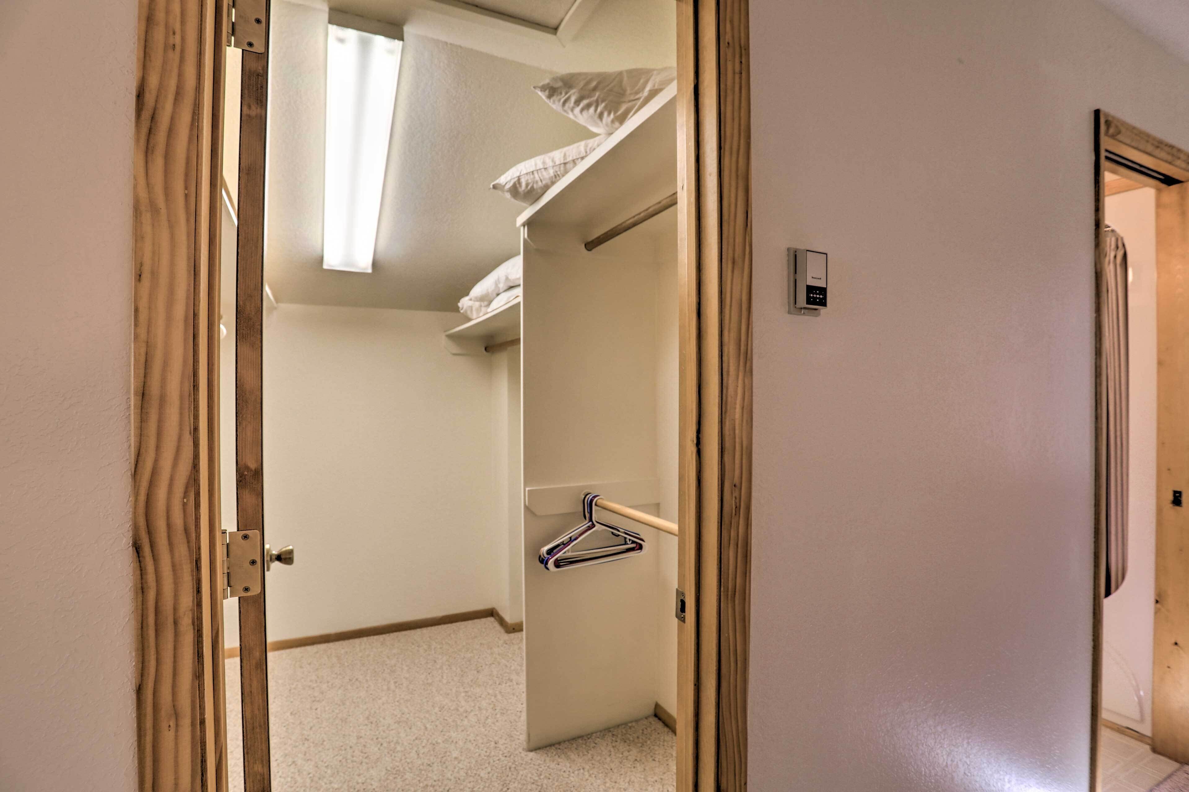 Un pasillo estrecho con un marco de puerta de madera, un perchero y una ventana pequeña con una cortina blanca.