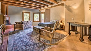 Un dormitorio amplio con una cama grande, una mecedora, una mesa de madera y una alfombra estampada.