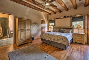Une chambre spacieuse avec un grand lit, un plancher en bois, une armoire et un ventilateur de plafond.