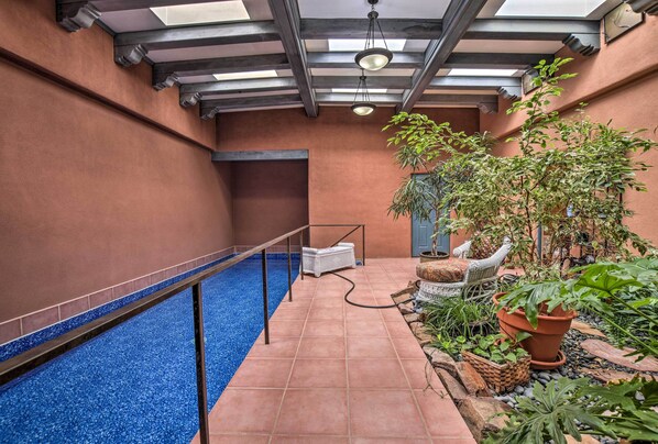 A pool area with a blue tiled floor, a white lounge chair, and potted plants. - Stunning Santa Fe Sw-style Getaway w/ Indoor Pool! (Santa Fe)