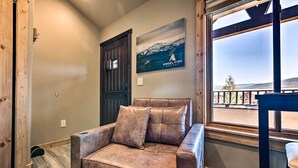 Een gezellige kamer met een leren bank, een houten deur, uitzicht op de bergen en een bord met Angel Fire Resort.
