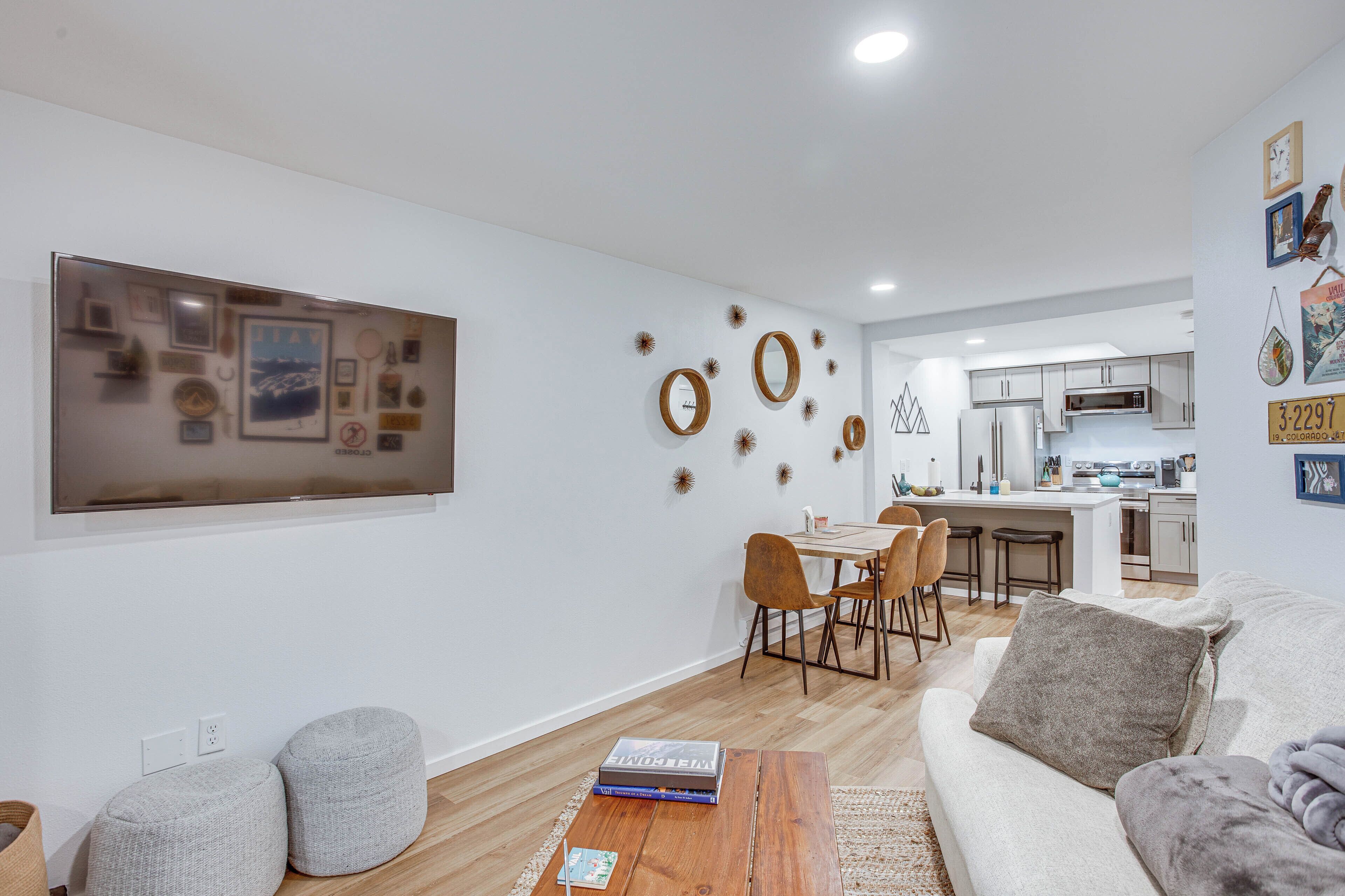 A modern living room with a sofa, ottomans, a coffee table, and a dining area with chairs and a table.