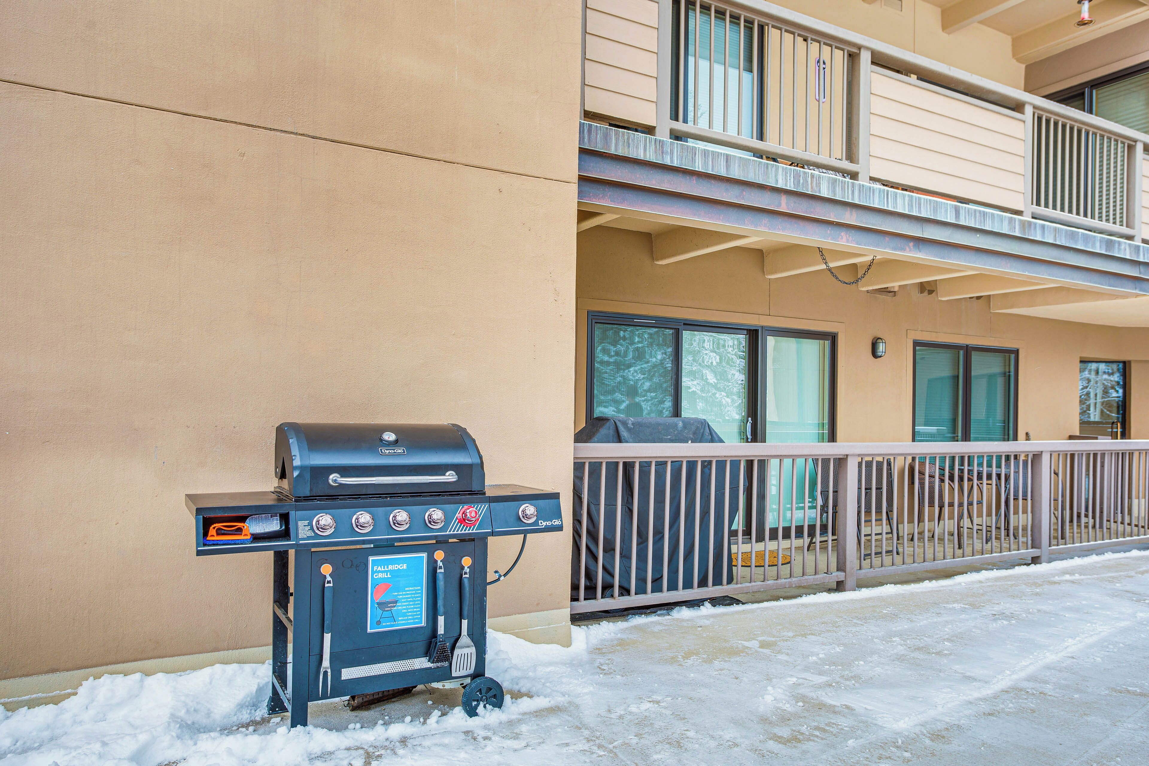 A barbecue grill outside a building with a balcony.