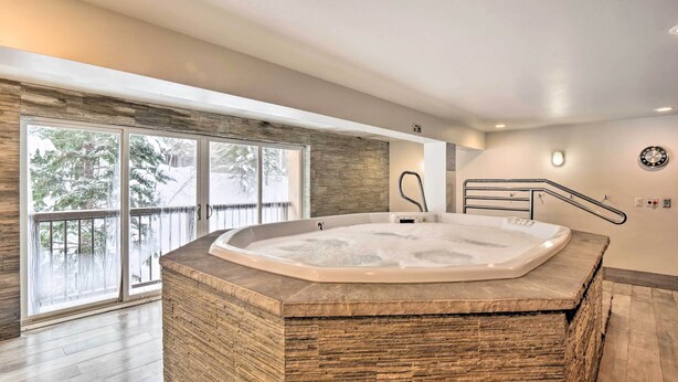 Ein modernes Badezimmer mit einer freistehenden Badewanne, großen Fenstern und Blick auf Bäume.