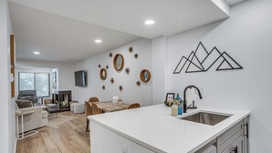 Eine moderne Küche mit weißer Arbeitsplatte, Spüle aus Edelstahl und Holzelementen.