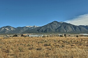 Un campo de hierba seca con montañas al fondo y algunos edificios.