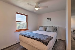 A bedroom with a bed, a ceiling fan, a window, and a framed picture on the wall. - Chic Studio w/ Grill - 25 Mins to Taos Ski Valley! (El Prado)