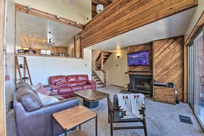 Una sala de estar acogedora con chimenea, sofá de cuero y televisor.