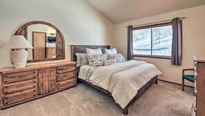 Ein Schlafzimmer mit einem großen Bett, einer Kommode mit Schubladen, einem Spiegel und einem Fenster mit Vorhängen.