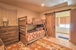 Un letto a castello con una scala in legno, un comò di legno e un tappeto decorato.