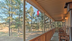 A covered porch with wooden railings, a row of wooden chairs, and a view of a golf course. - Ruidoso 'lil Mountain Getaway' w/ Golf Course View (Ruidoso)