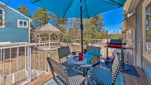 Une terrasse avec une table, des chaises et un barbecue.